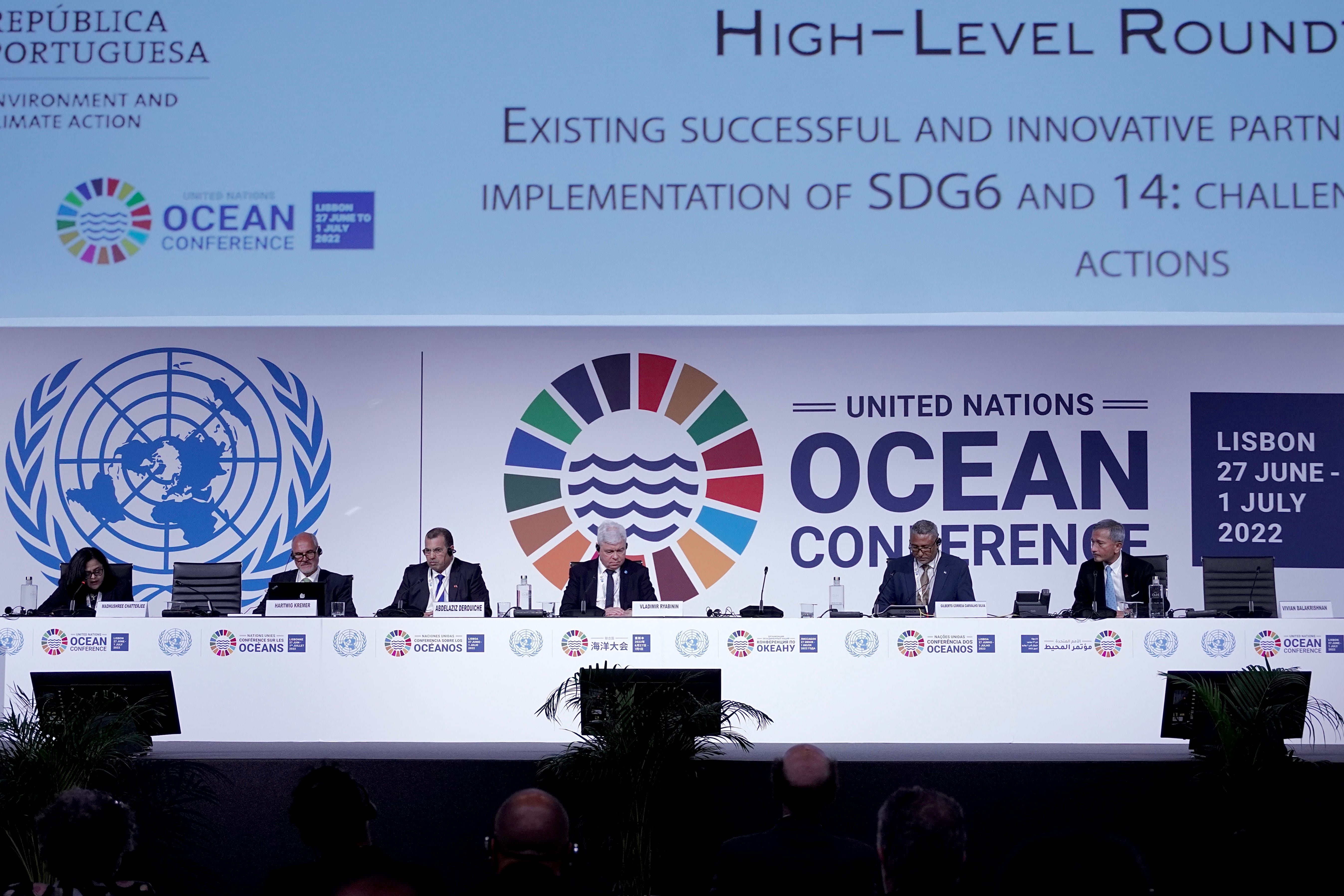 Panelists at United Nations Ocean Conference in Lisbon. Logos on stage, audience in foreground.