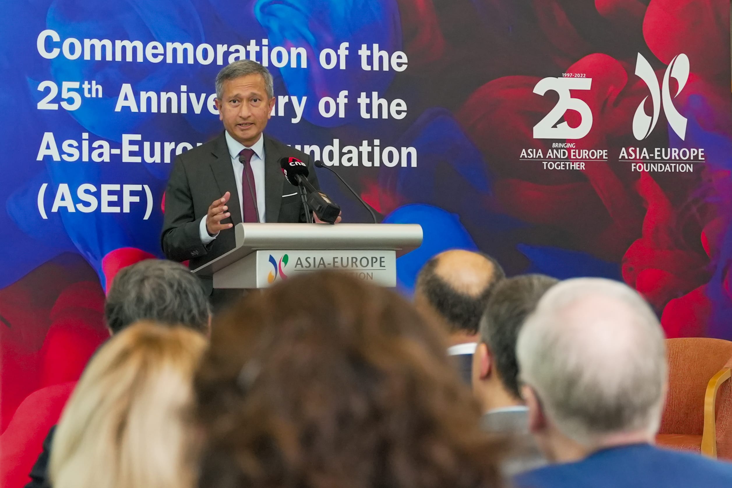 Man at podium speaking at Asia-Europe Foundation 25th anniversary event. Audience visible.