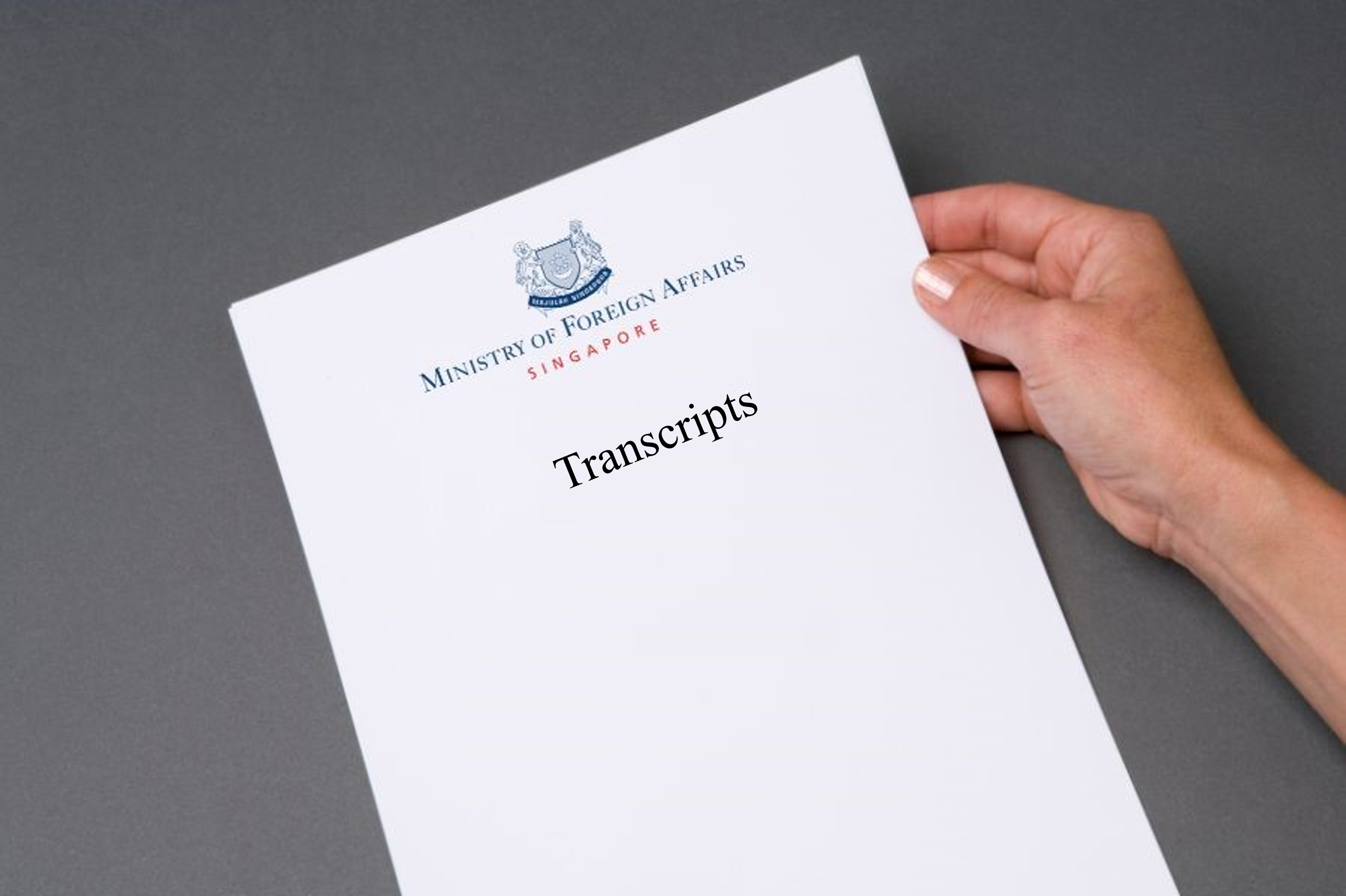 A hand holding a document titled "Press Statements" from Singapore's Ministry of Foreign Affairs.