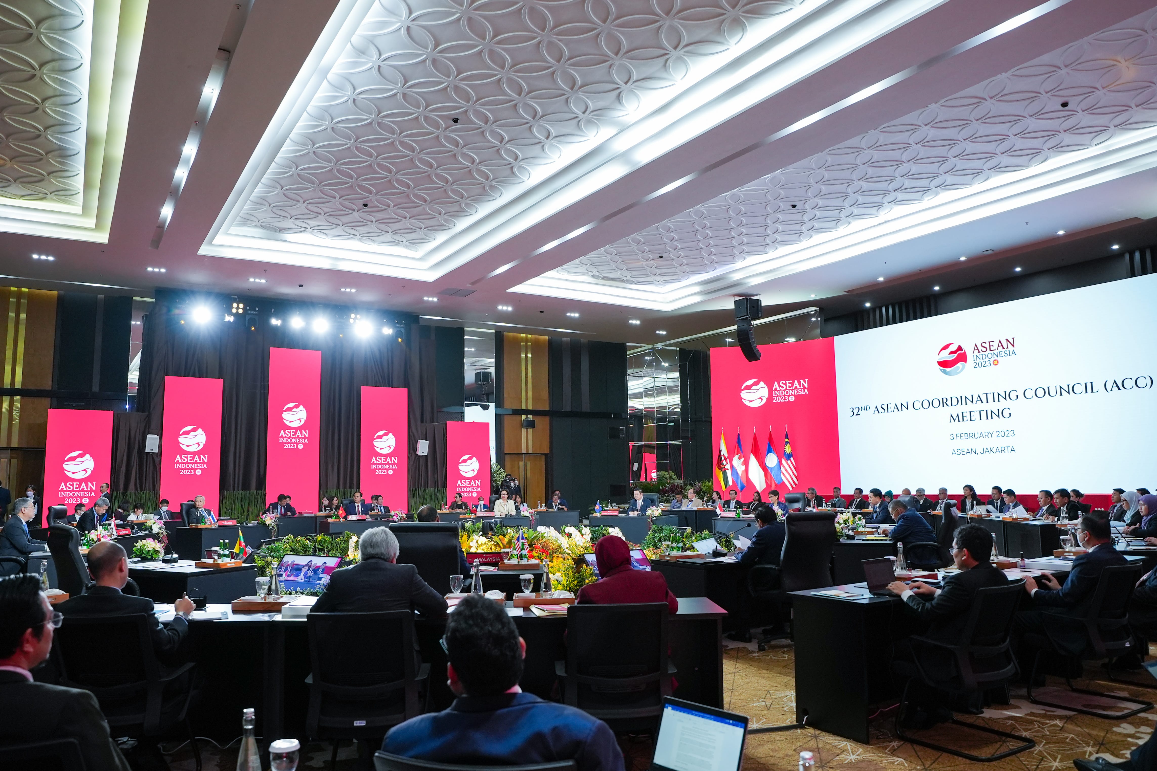 ASEAN meeting with attendees seated at tables facing flags and a screen.
