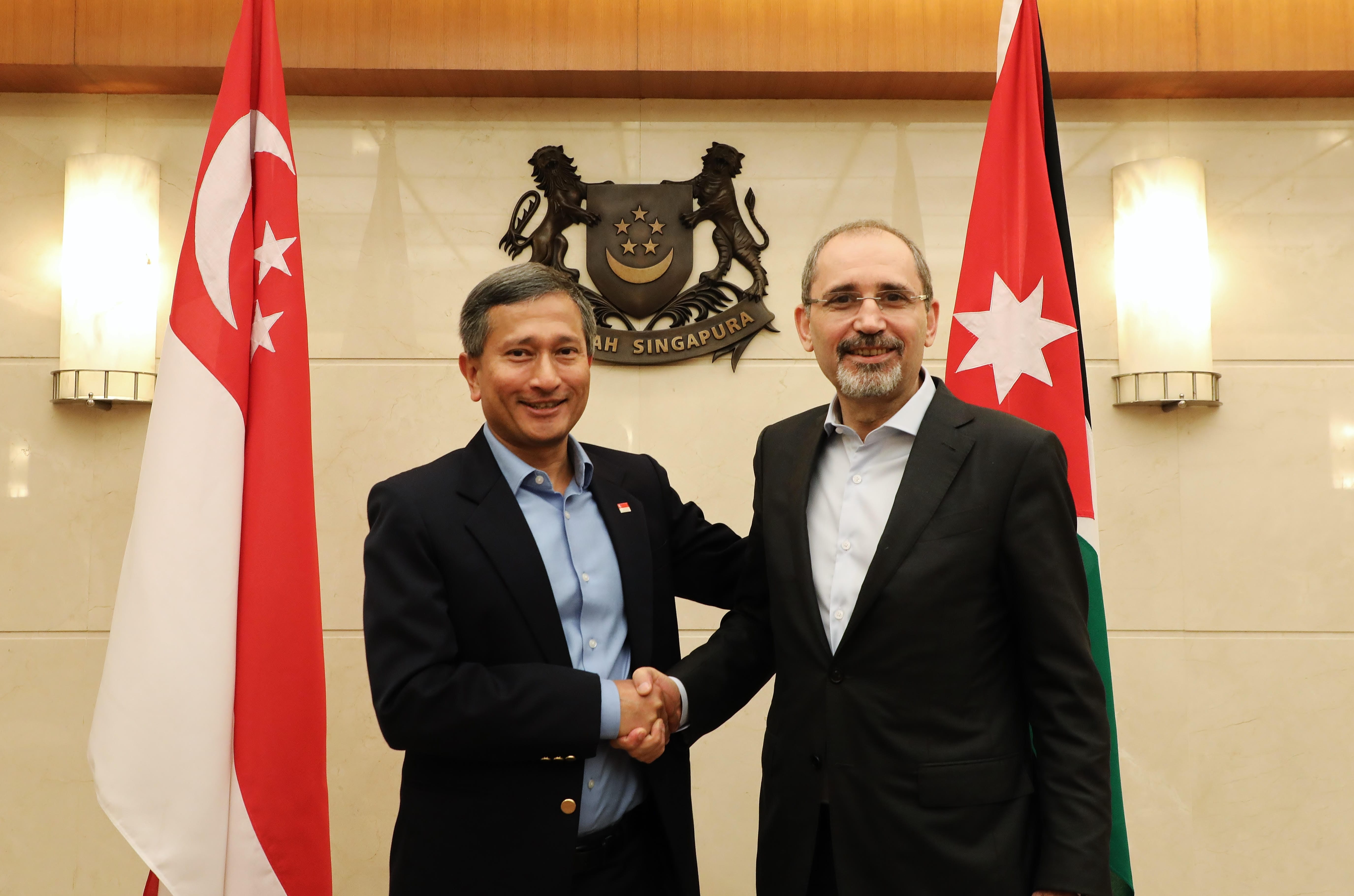 Three people seated at a banquet table with floral centerpiece, laughing.