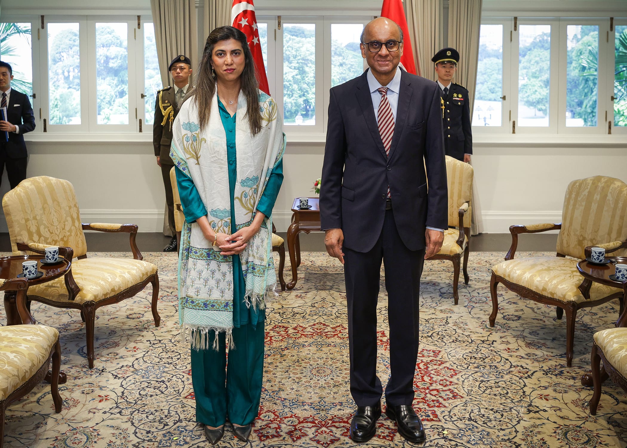 Singapore's President Tharman Shanmugaratnam with a woman, flags and officials in background.