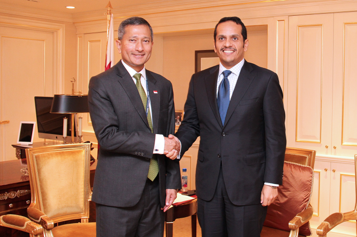 Two men in suits are shaking hands in an office setting.