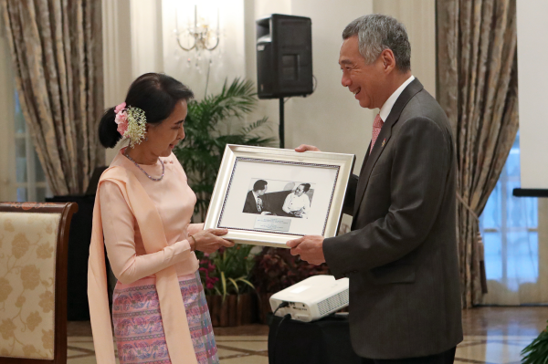 Aung San Suu Kyi gives framed photo to Lee Hsien Loong.
