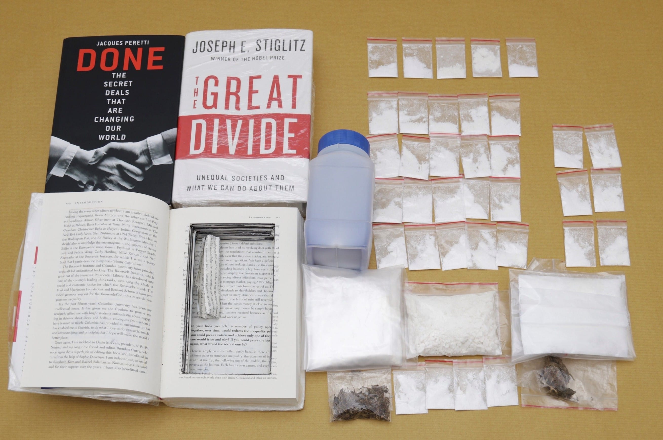 Books "Done" and "The Great Divide," with clear plastic bags of white powder, a few with dark substance.