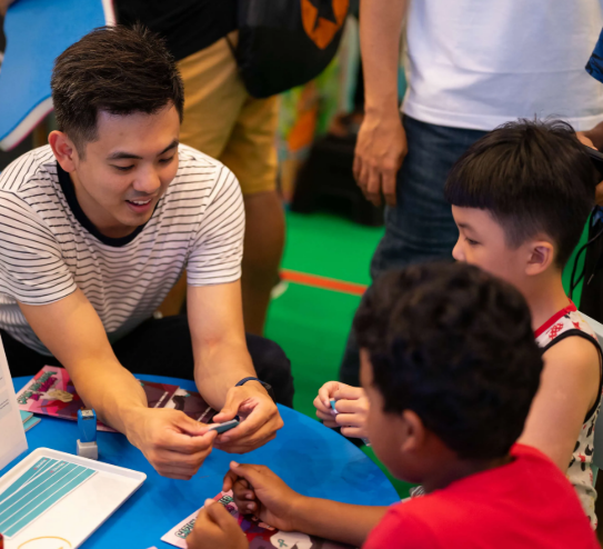 man folding some paper with kids