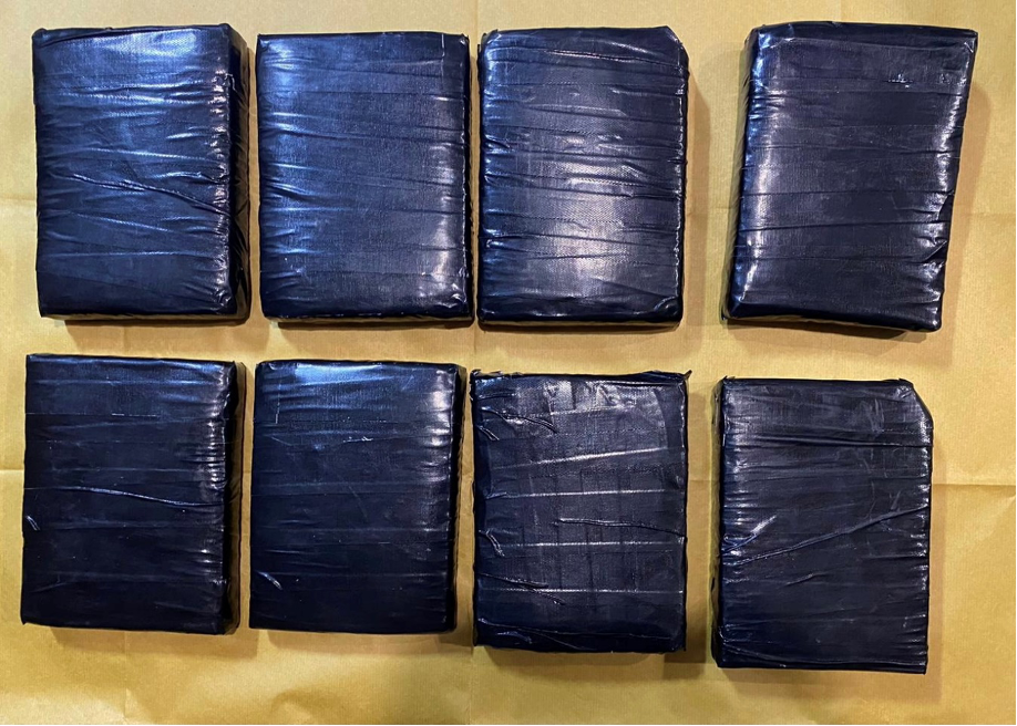 Eight black rectangular packages wrapped with tape, arranged on a tan surface.