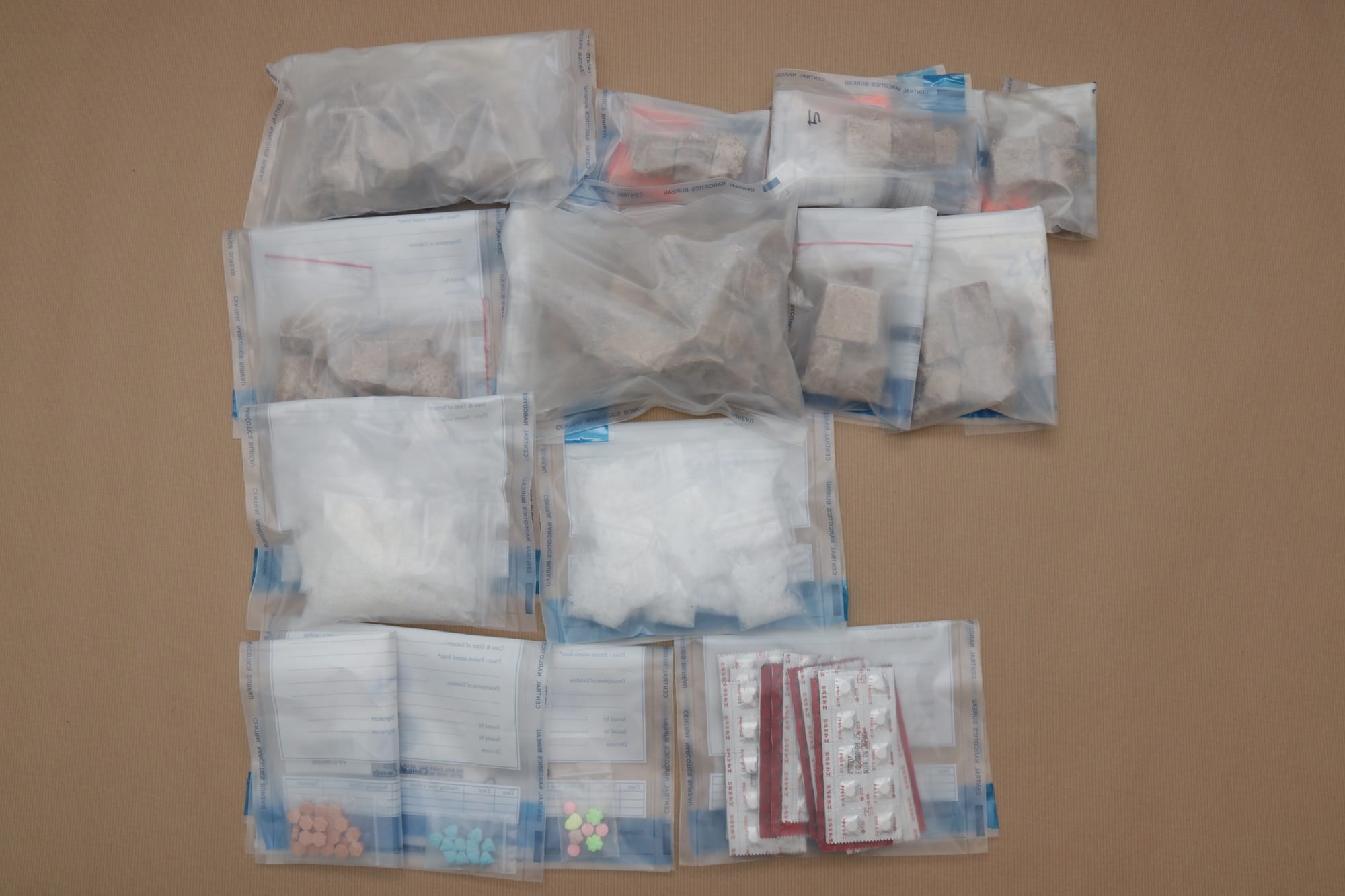 Drugs: Bags of brown chunks, white powder, loose pills and blister packs on brown surface.