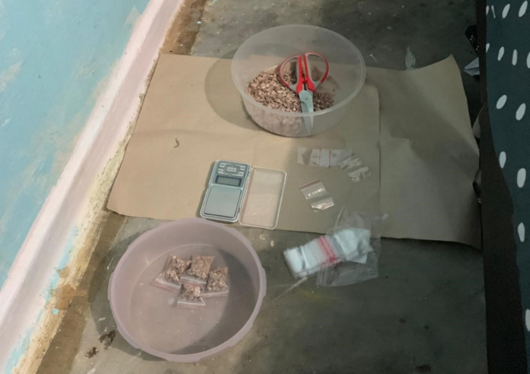 Brown chunks in plastic containers with small bags, digital scale, and scissors on paper.