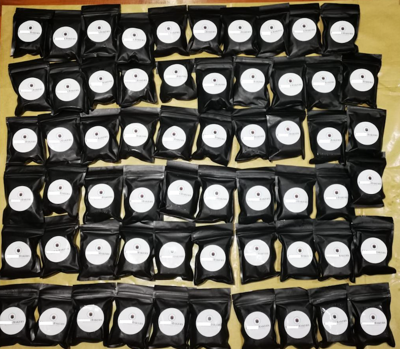 Many black bags with round white labels arranged on a yellow surface.