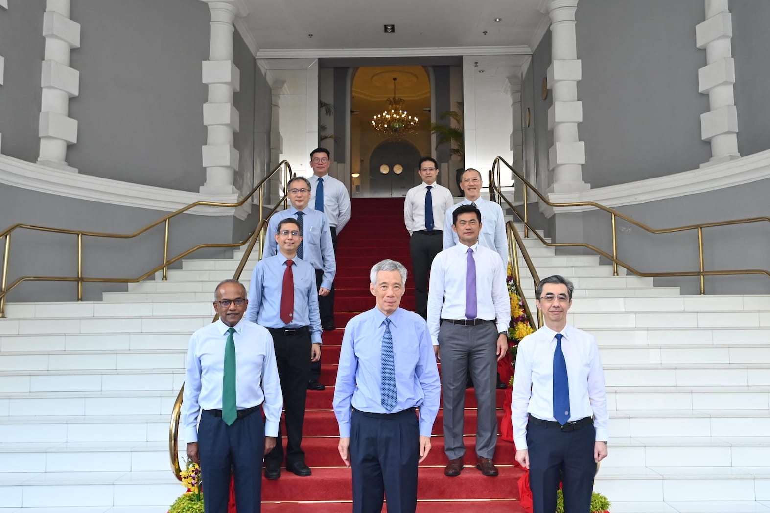 Group portrait on steps; Lee Hsien Loong and others in shirts and ties, red carpet on white steps.
