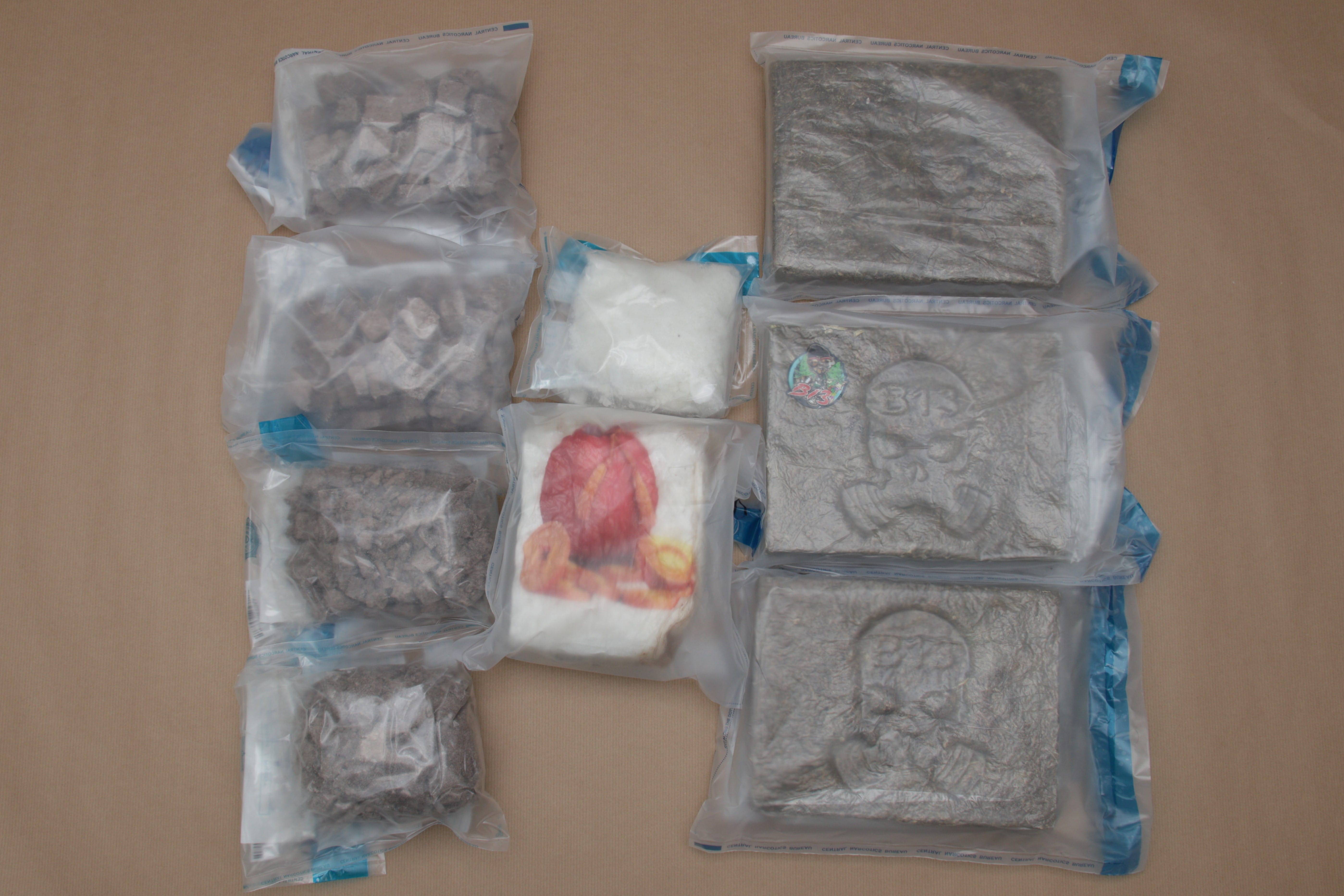 Sealed bags with powders, chunks, and pressed squares, one with skull motif and another with a fast food logo.