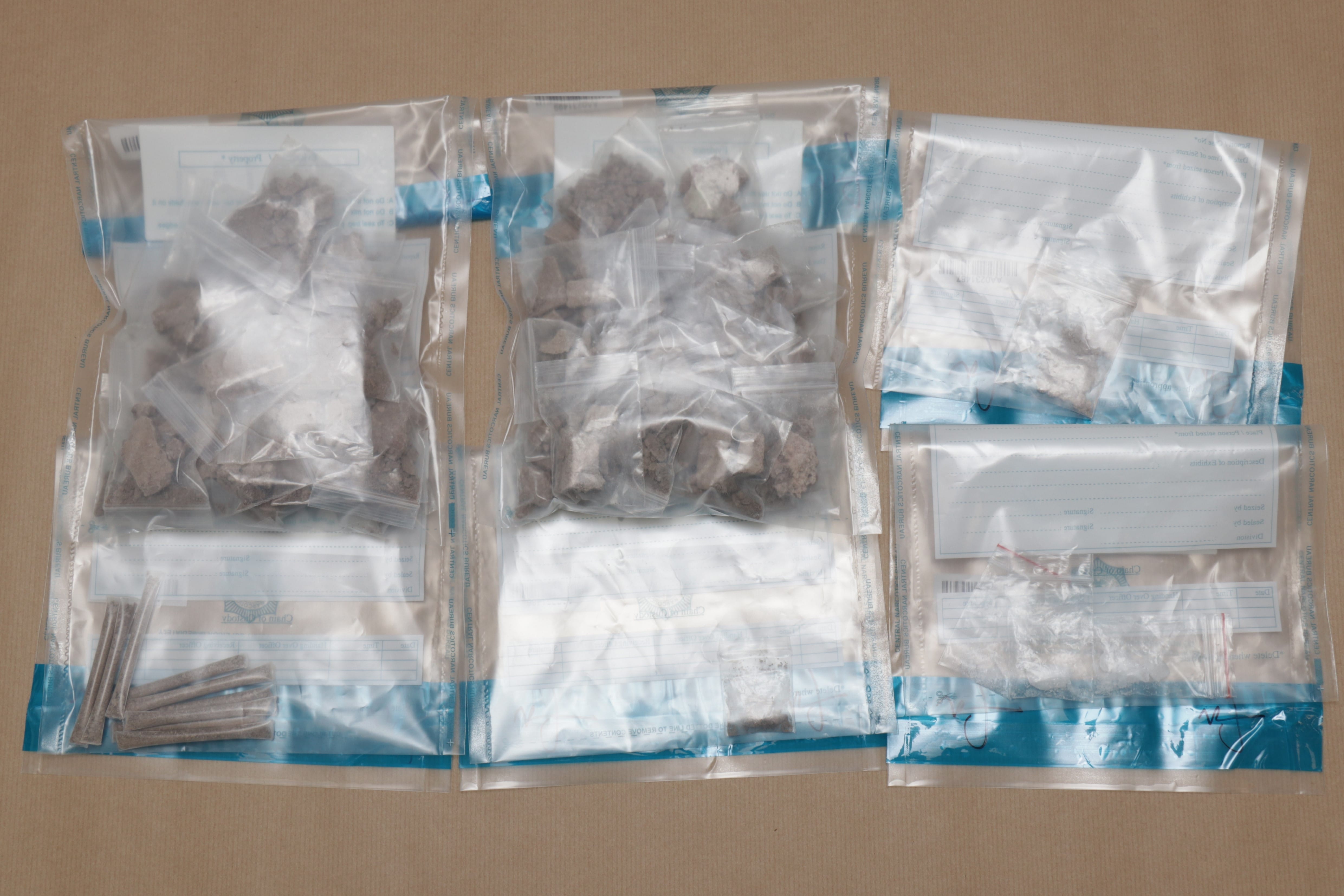 Three evidence bags with tan powder/rocks. The left bag also contains brown sticks.