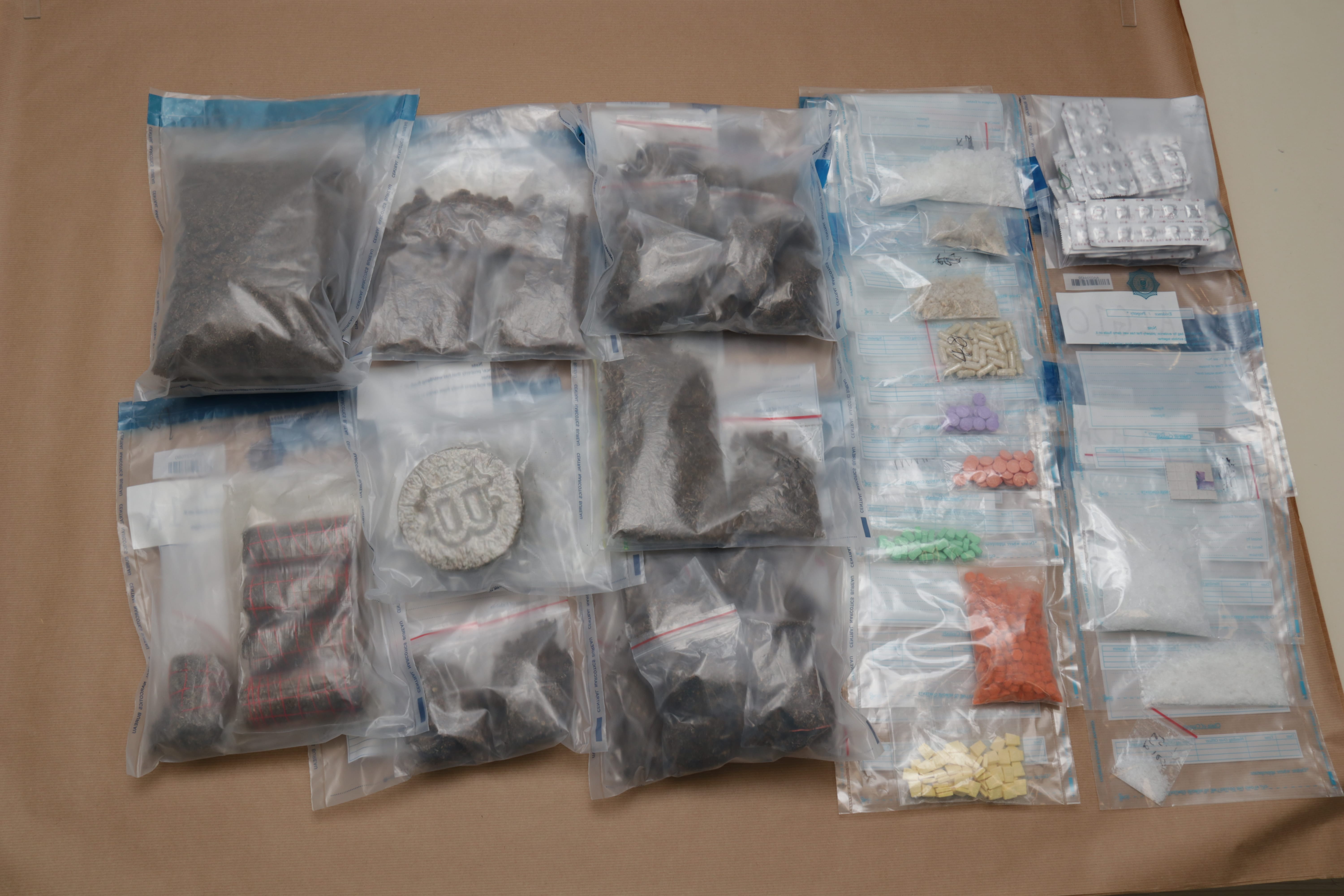 Bags with pills, powders, and substances on brown paper.