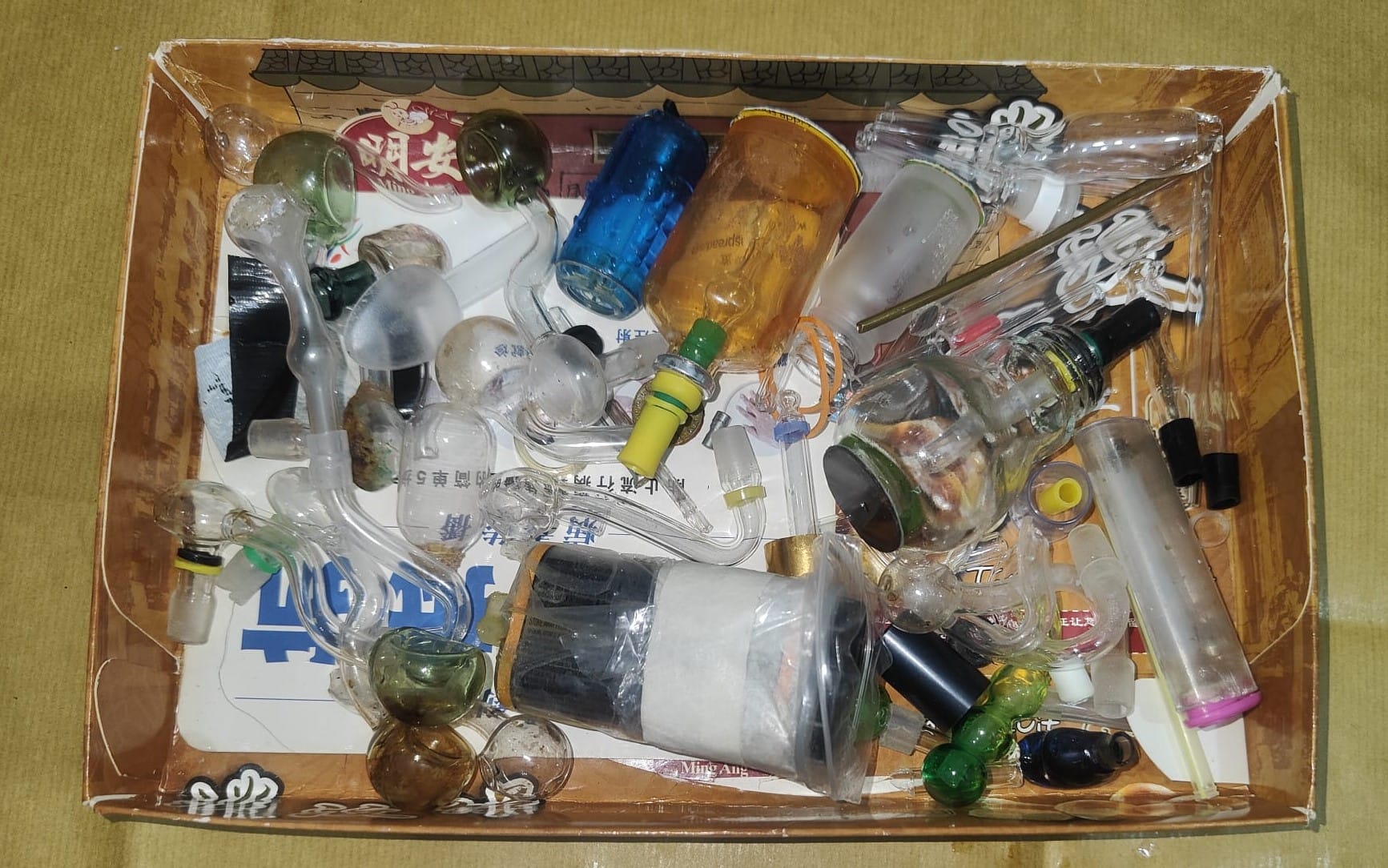 Collection of glass pipes and containers in a cardboard box.