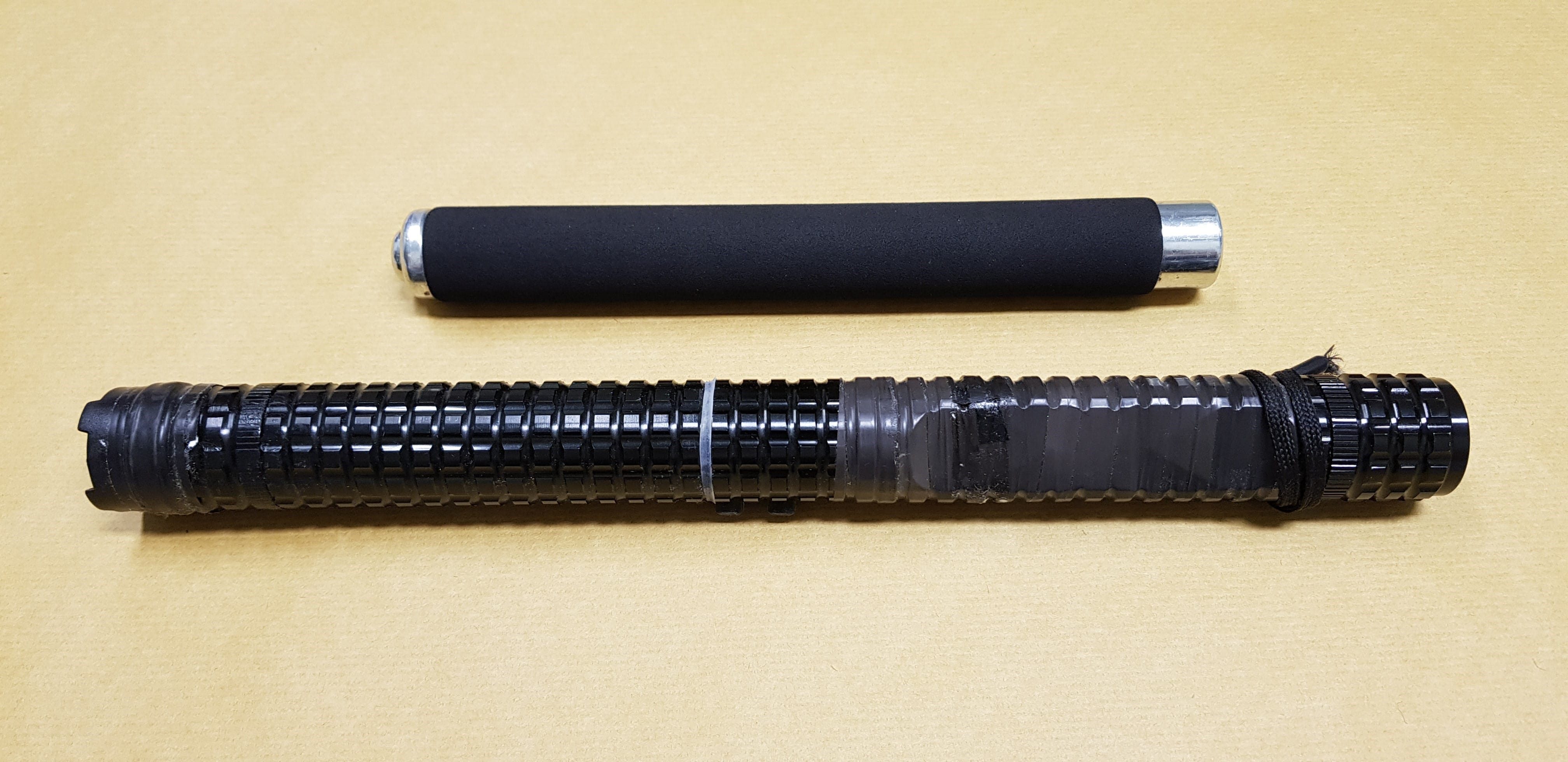Two batons: a short black foam one and a longer telescoping black one with tape.