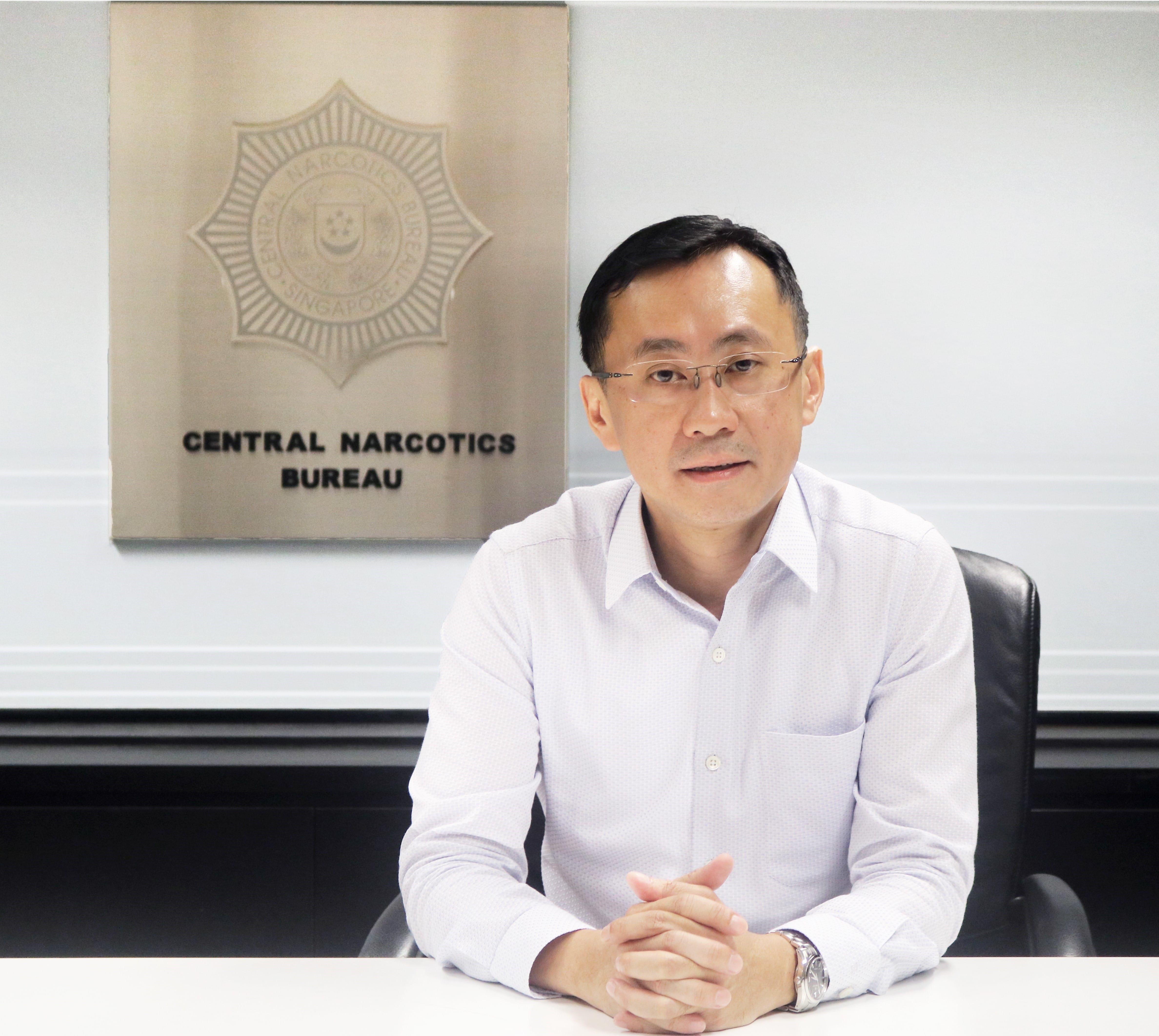 Sebastian Tan seated at the table with CNB signage behind him.
