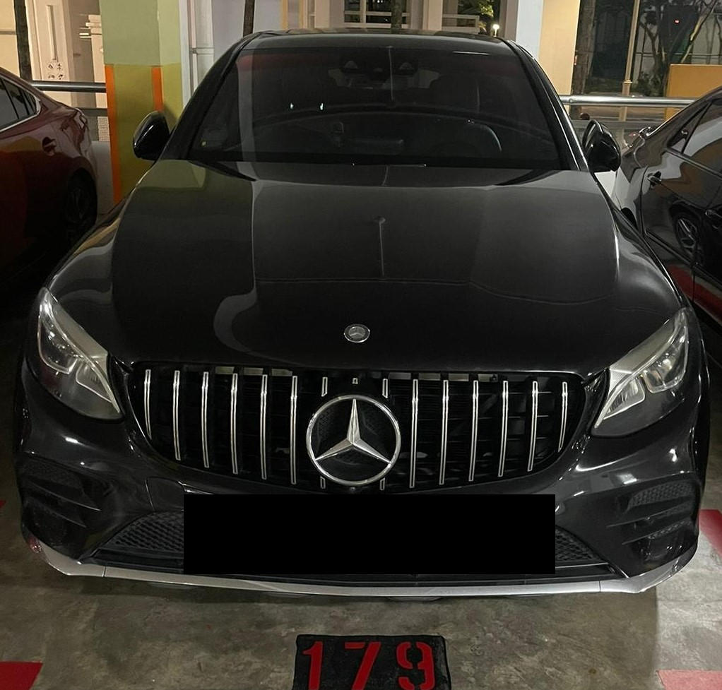Black Mercedes-Benz car parked in a garage, front view. License plate is obscured.