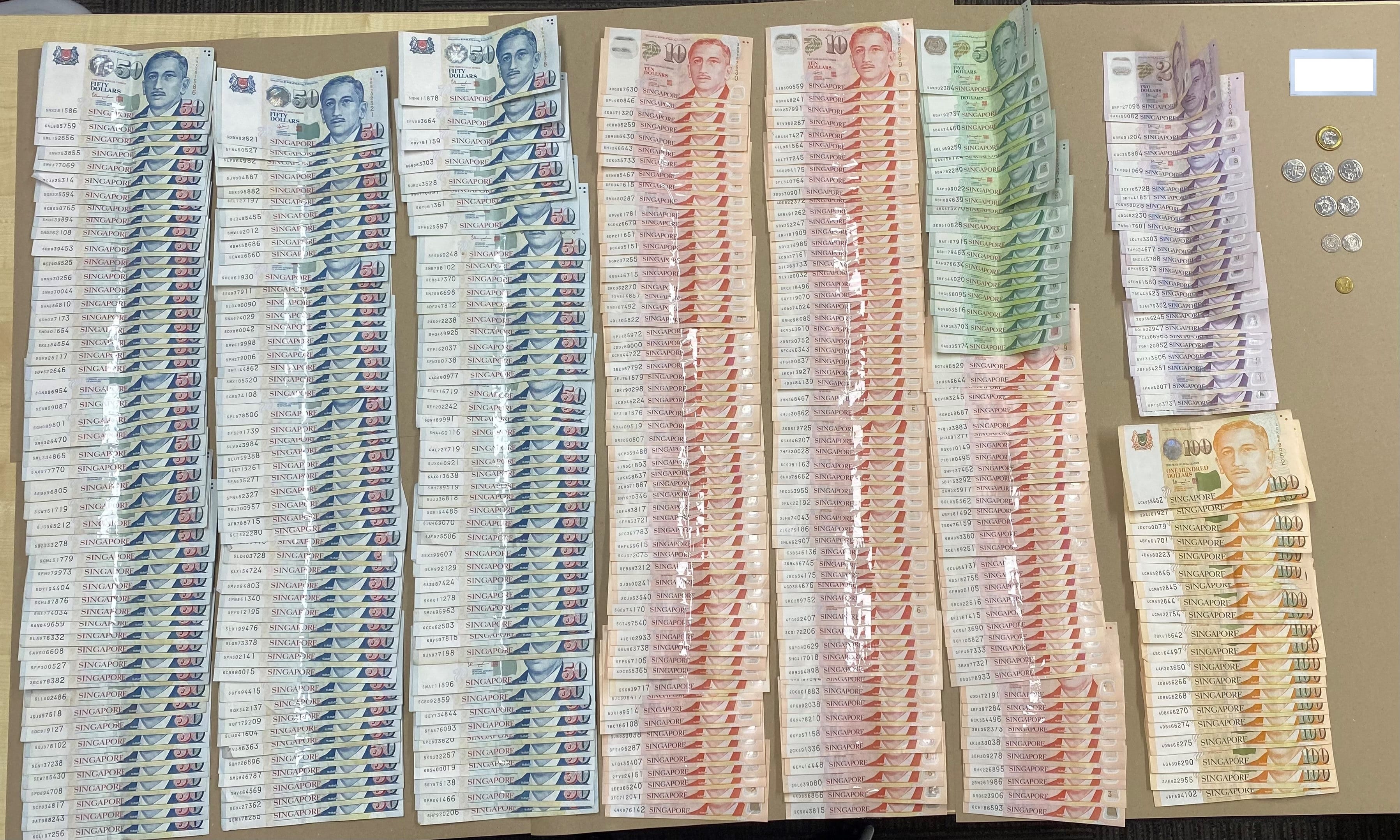 Stacks of Singapore dollar banknotes (50, 10, 5, 2, 100), plus coins.