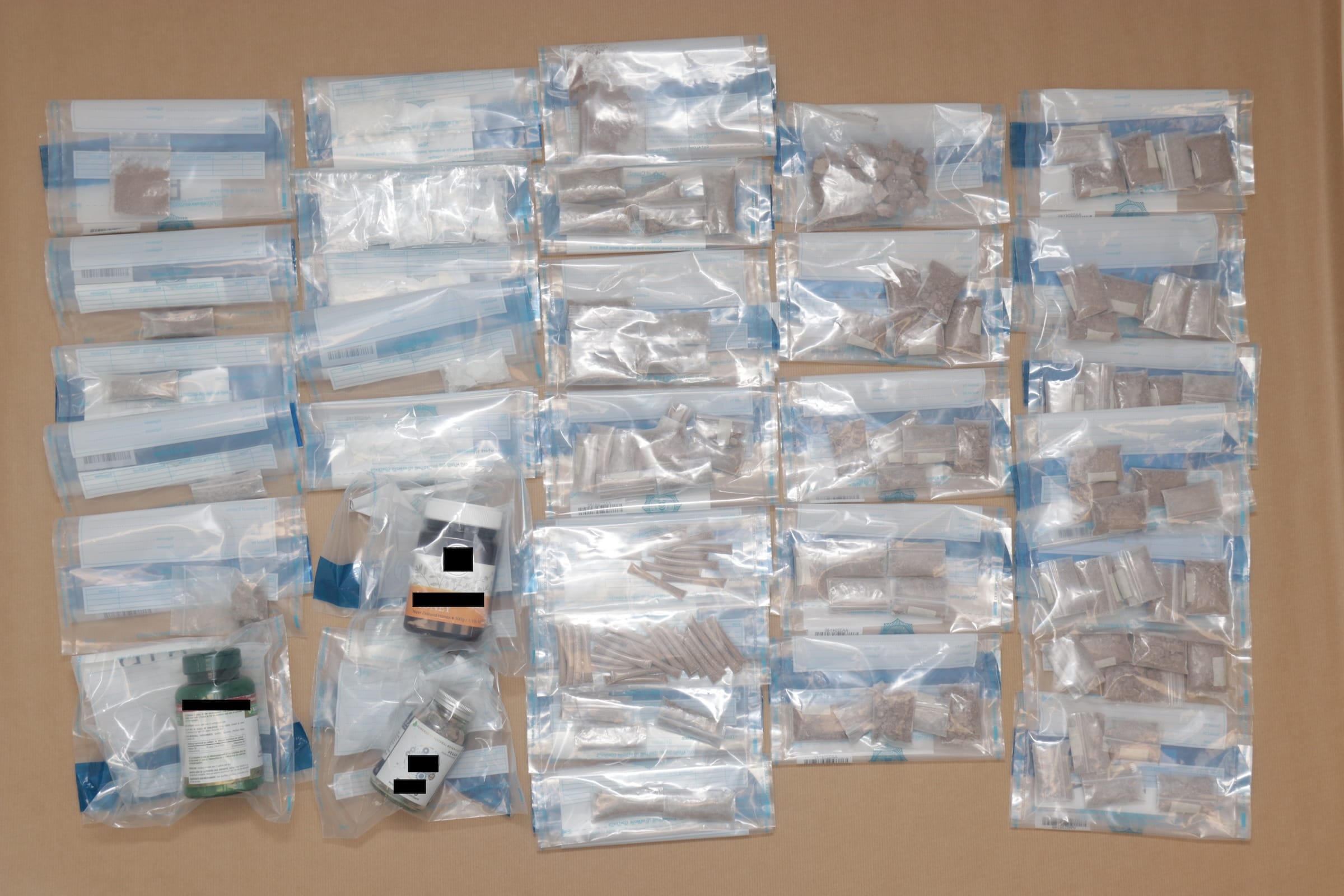Multiple clear bags and jars containing various substances on a brown surface.