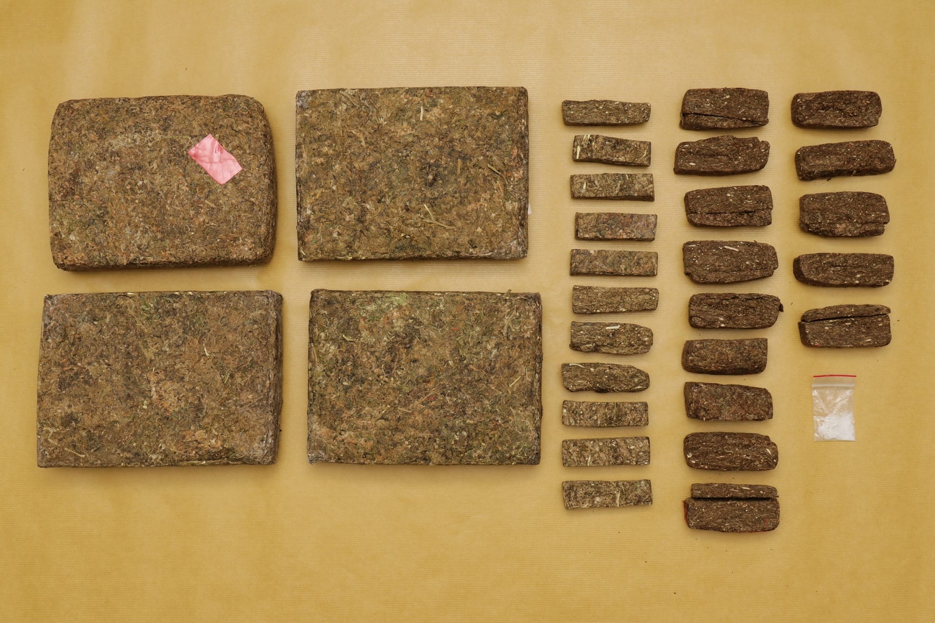 Four rectangular blocks, smaller bricks, & clear bag with white powder on a tan background.
