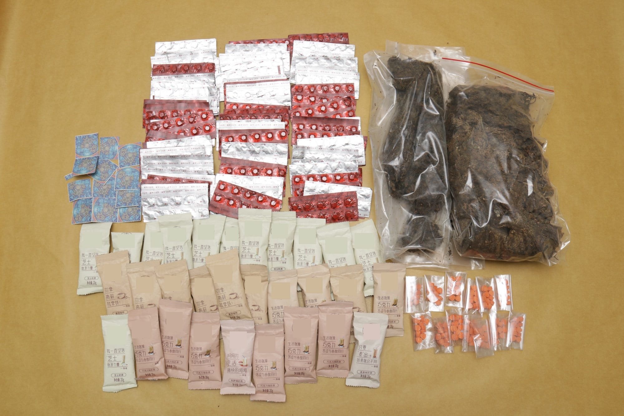 Pills in blister packs, loose tablets, packets of tea mix, and two bags of dark dried plant material.