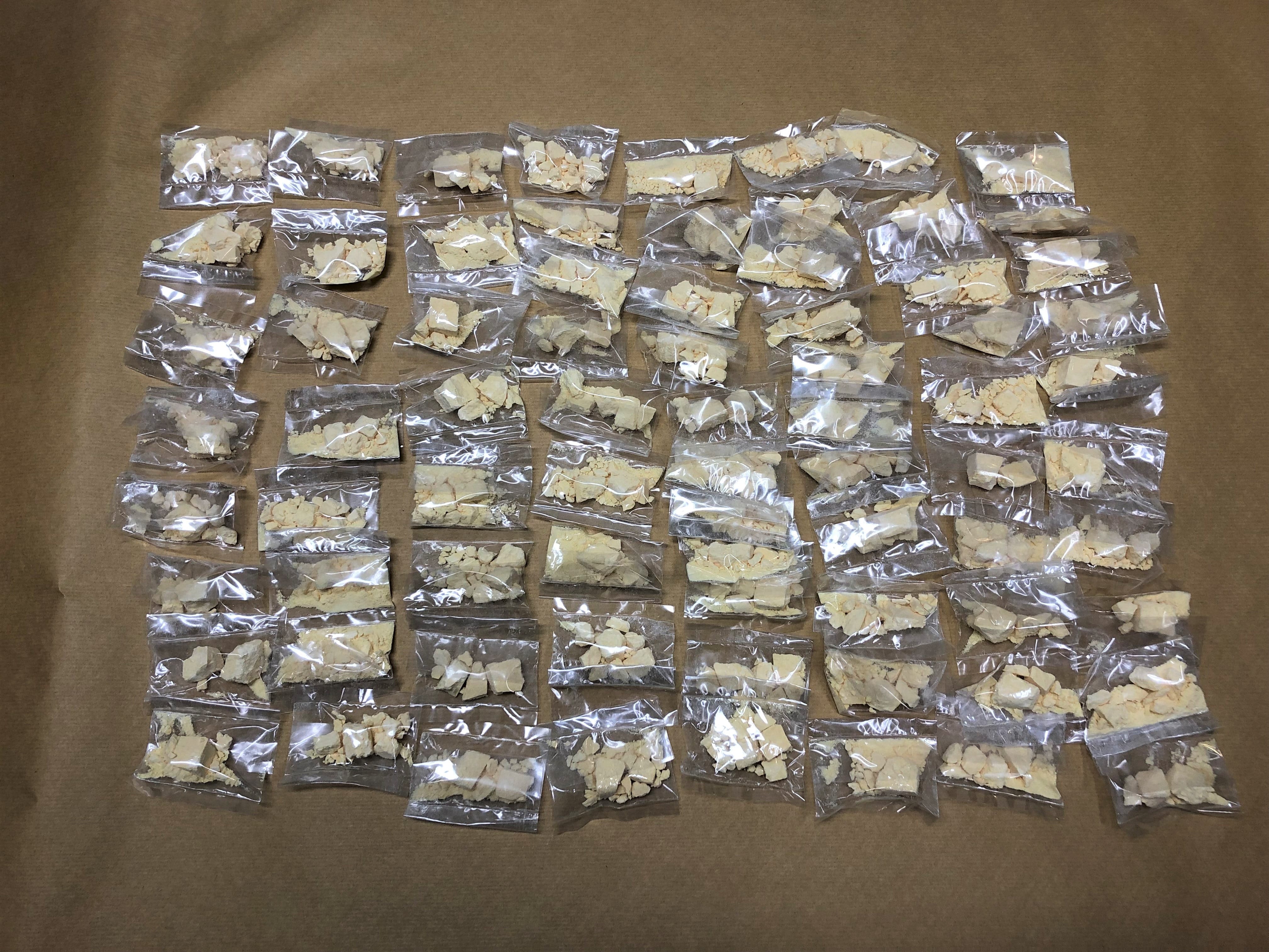 Forty+ clear plastic bags with crumbly tan contents, laid on tan paper.