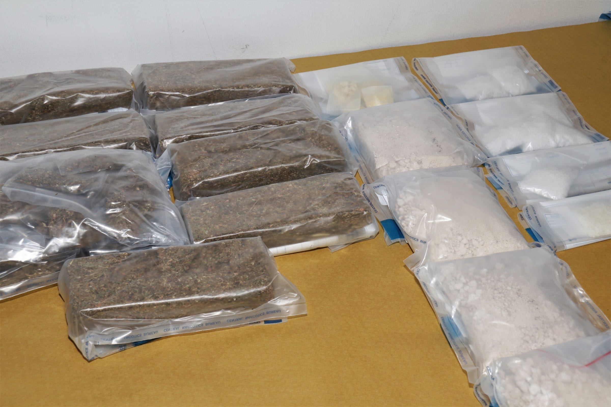 Plastic bags with probable drugs: rectangular bricks and white powders. "Central Narcotics Bureau" printed on bags.