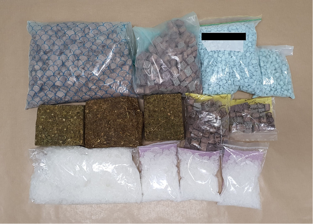 Multiple bags containing pills, cubes and plant matter are laid out on a table.