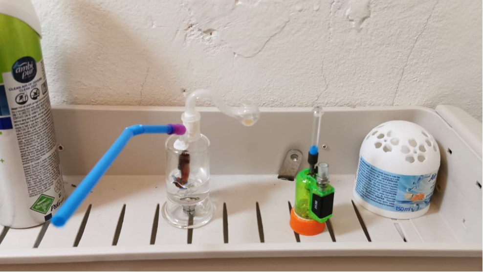 Shelf with Ambi Pur, glass pipe with water, green vaporizer, and Air Wick air freshener.
