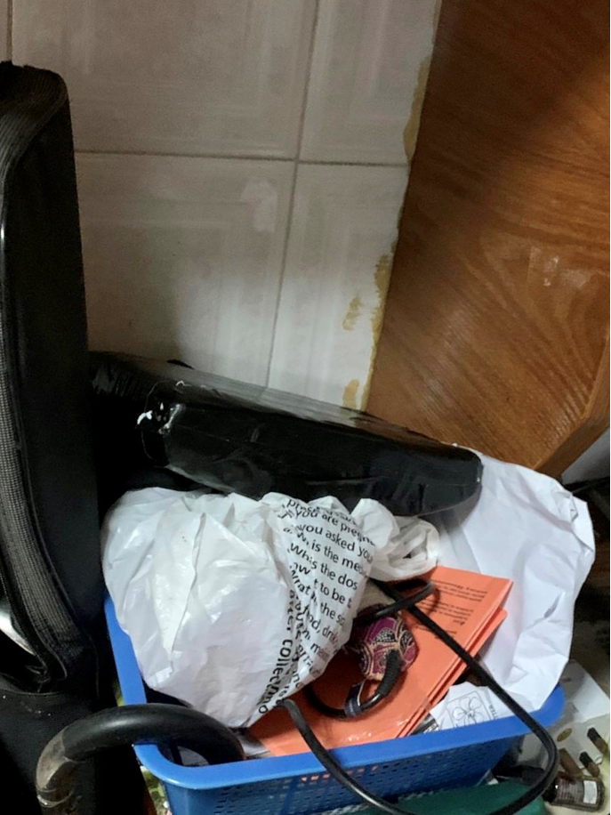 Messy blue basket with plastic bags, black package, and other items.