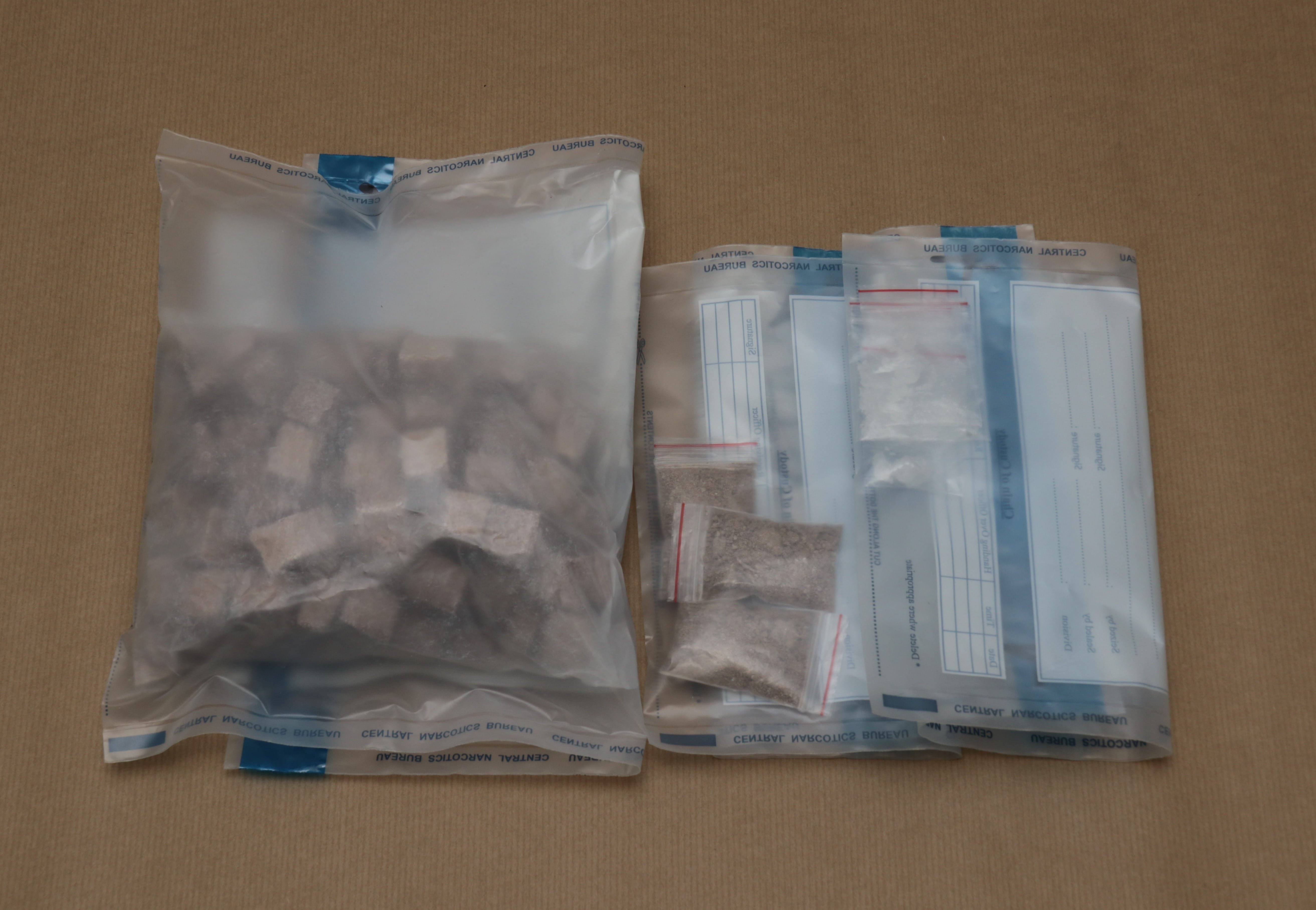 Clear bags with drugs, granular powder, and chunks; labeled "Central Narcotics Bureau."
