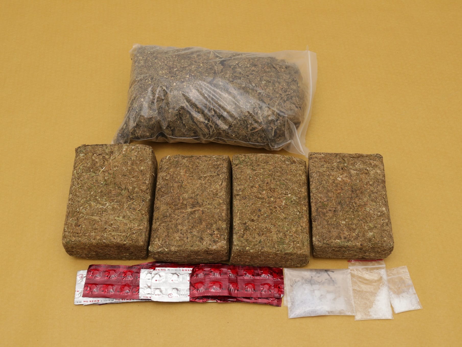 Bricks and bag of plant matter, red/silver blister pack, small clear bags with white powder.