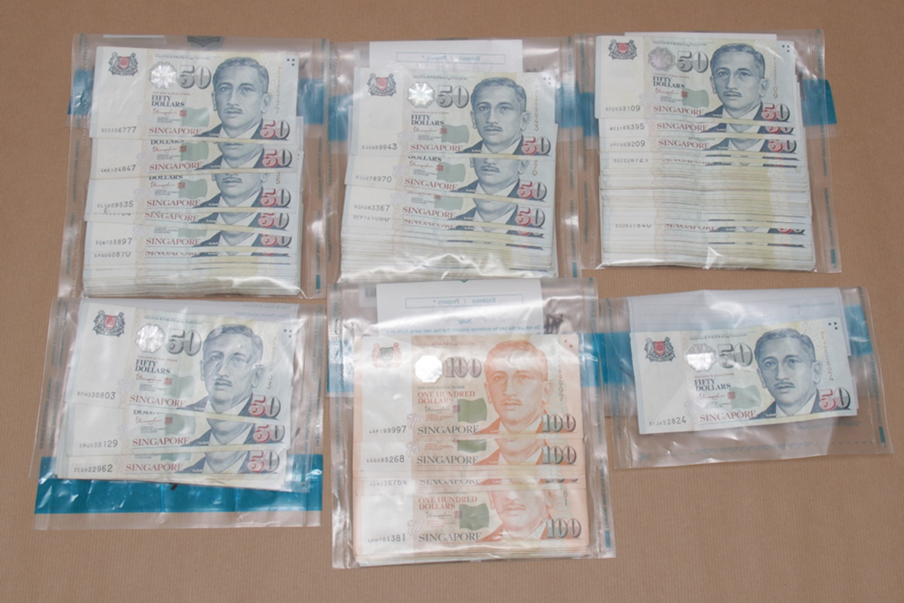 Stacks of Singapore 50 and 100 dollar bills sealed in plastic bags.