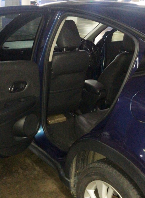 Open rear door of a blue car showing black leather seats.