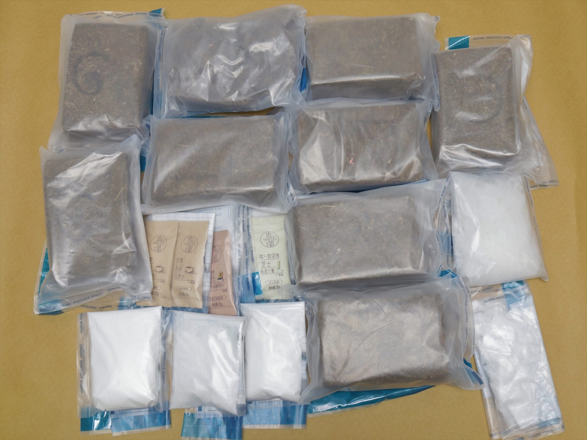 Packaged brown and white powders, likely narcotics, on a table. Clear plastic bags.