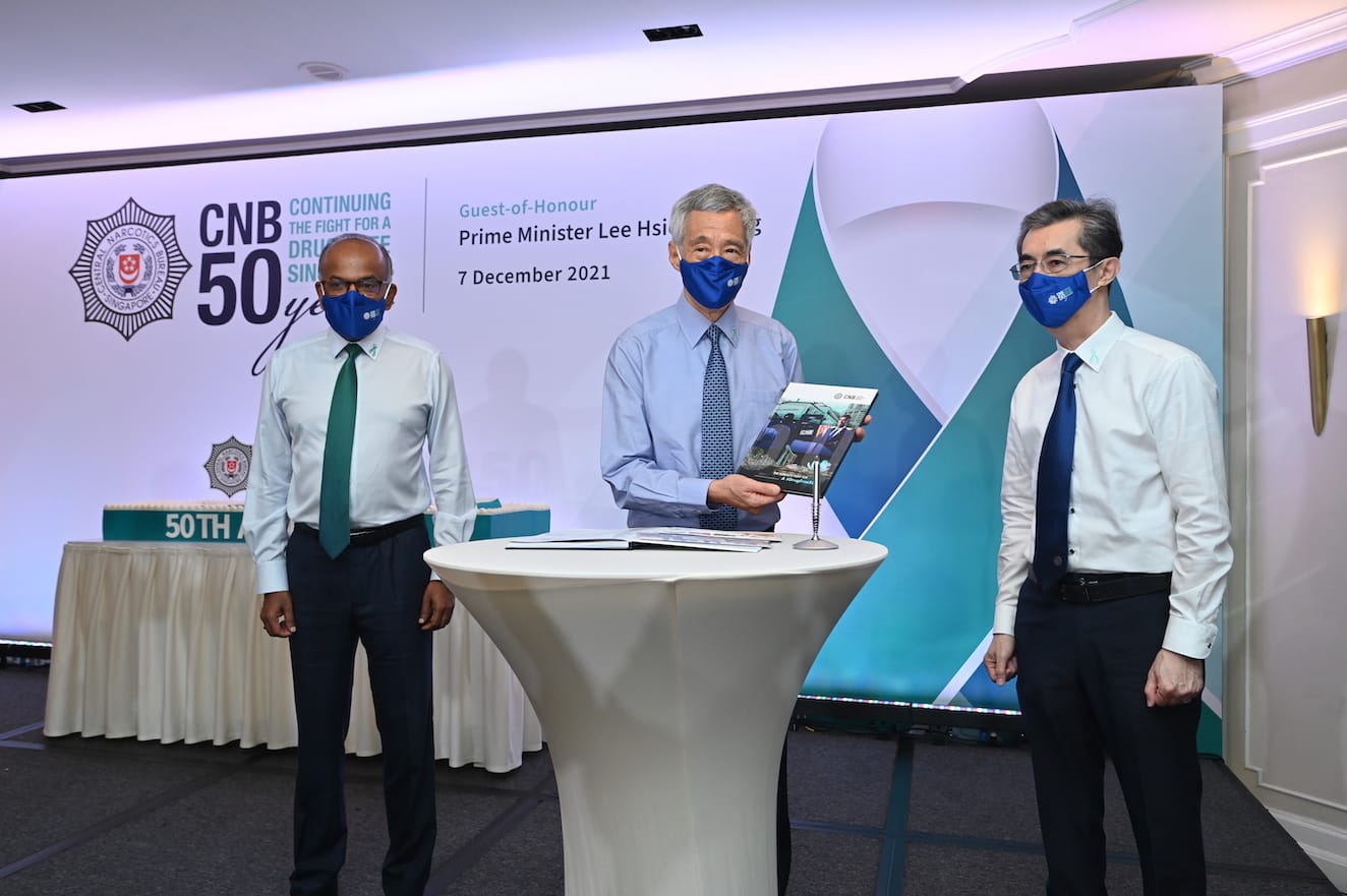 Singapore's National Stadium at night, lit with green lights, reflected in the water.