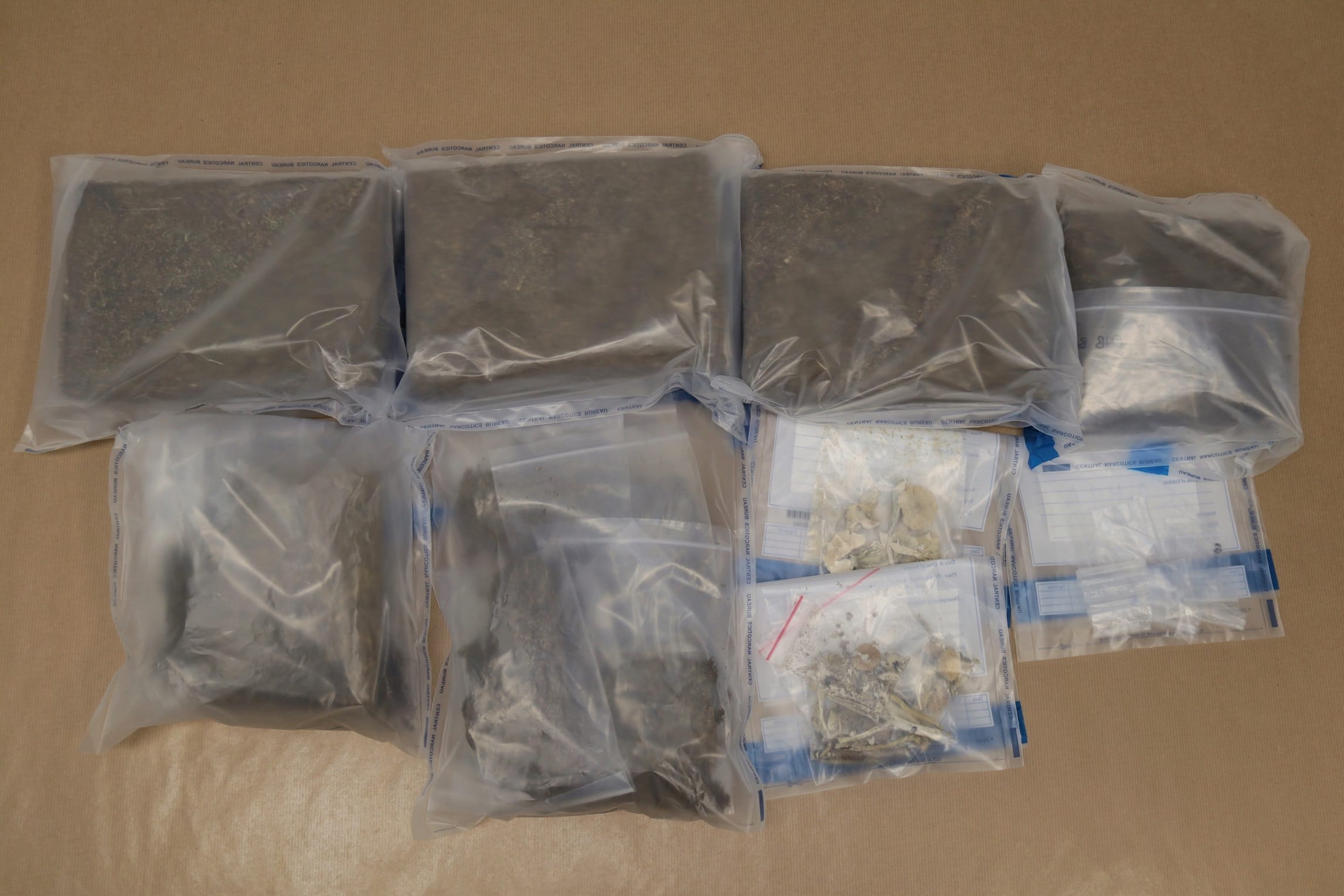 Multiple clear plastic bags, some containing plant matter, on a brown surface.