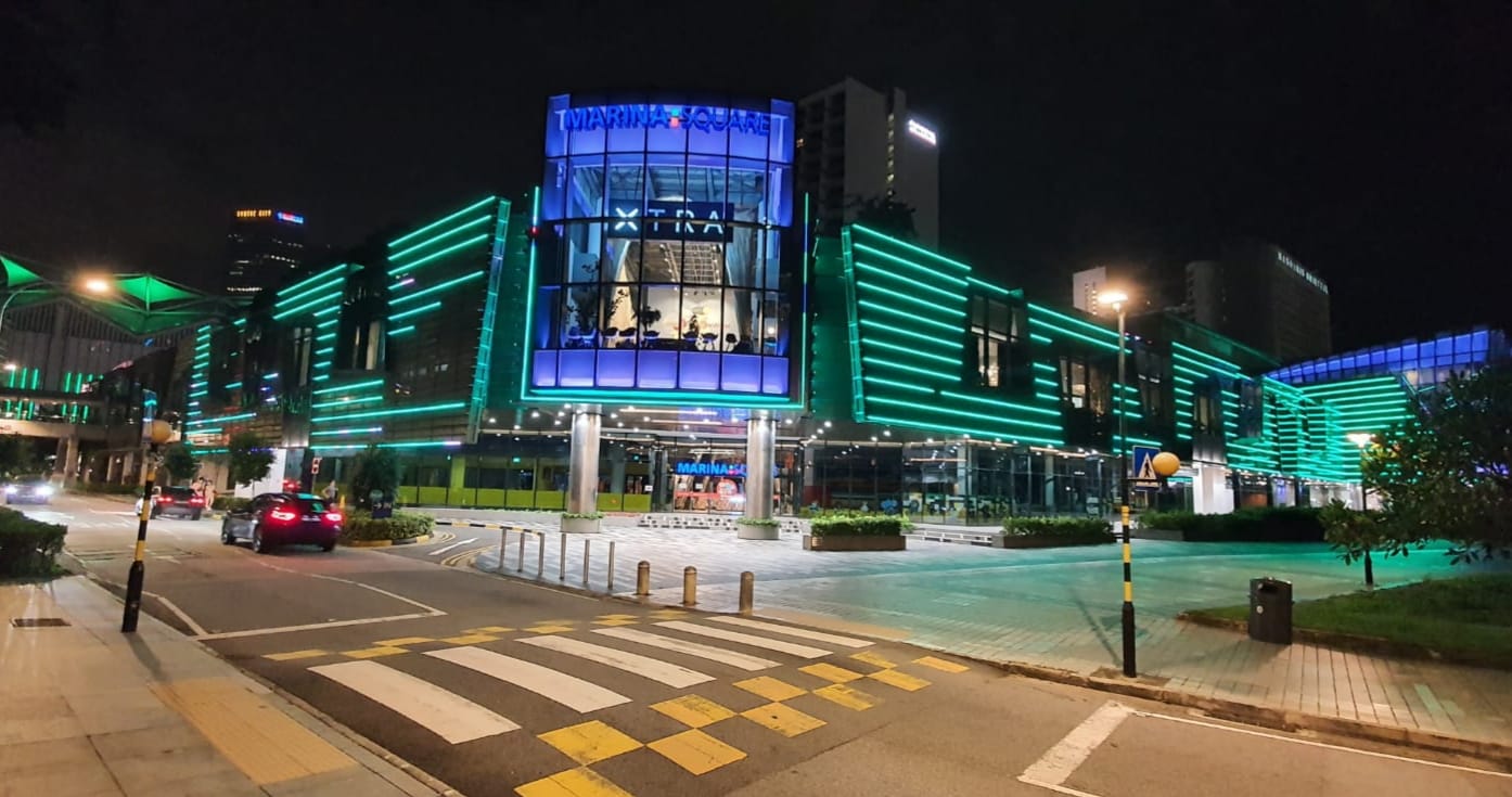 Illuminated Marina Square building at night, featuring blue and green neon lights. Cars on the road.