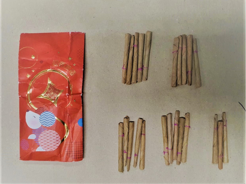 Red envelope with cartoon next to five groups of brown cigars bound with pink string.