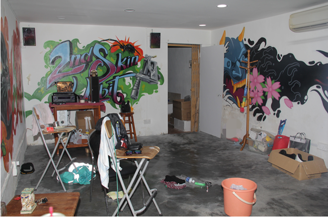 Room with graffiti-covered walls, folding chairs, and scattered items.