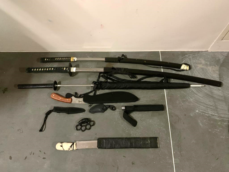 Collection of bladed weapons: katanas, knives, collapsible baton, and brass knuckles.