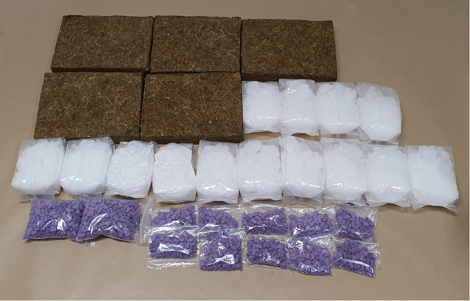 Four bricks, plastic bags with white crystalline contents, and bags of purple tablets on a surface.