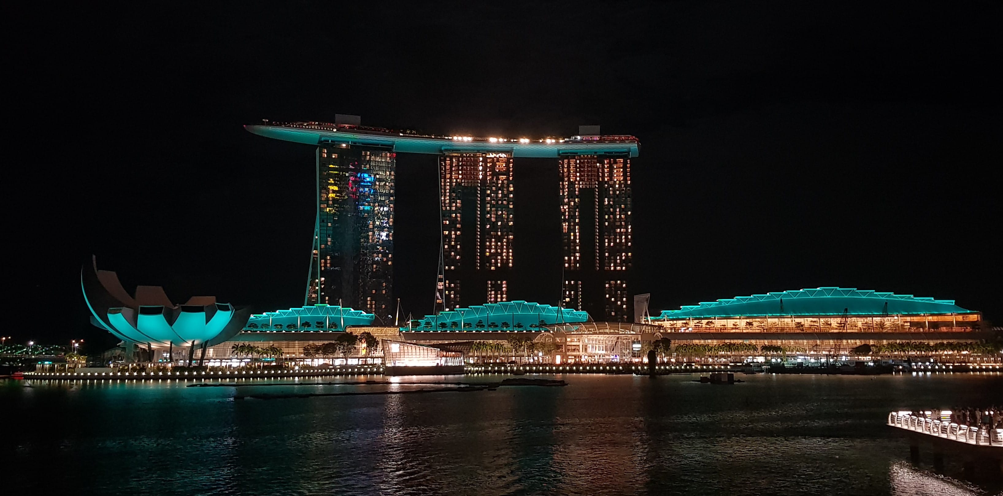 Marina Bay Sands, Singapore, at night with glowing buildings reflecting in the water.