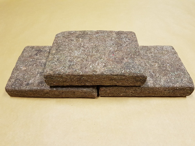 Three compressed coco coir bricks stacked on a brown surface.