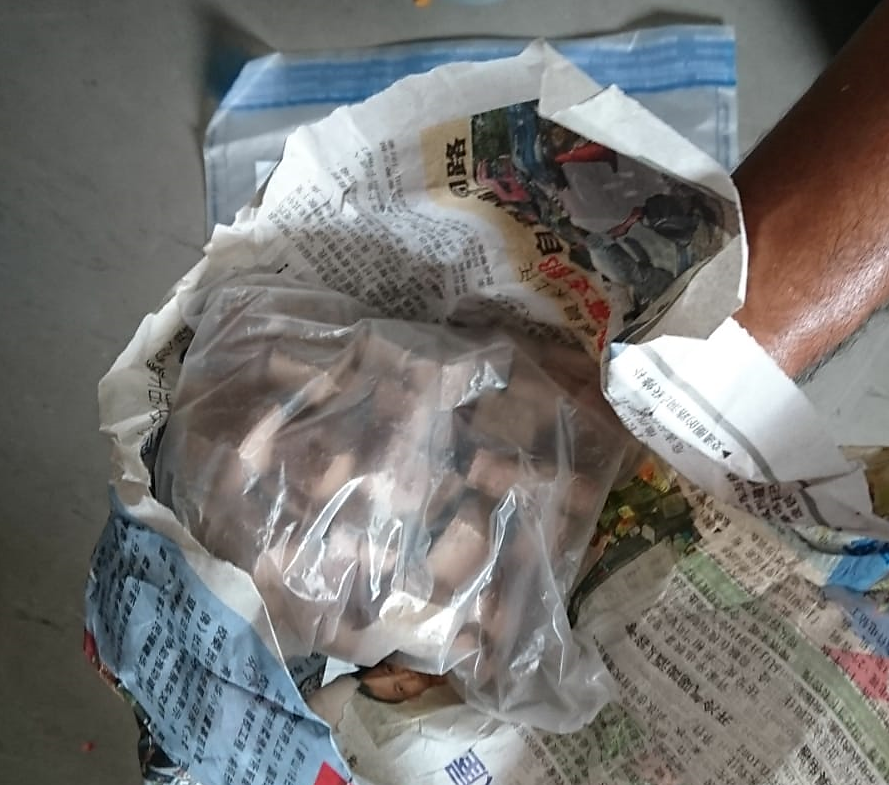 Bag of cubed meat wrapped in newspaper and plastic.