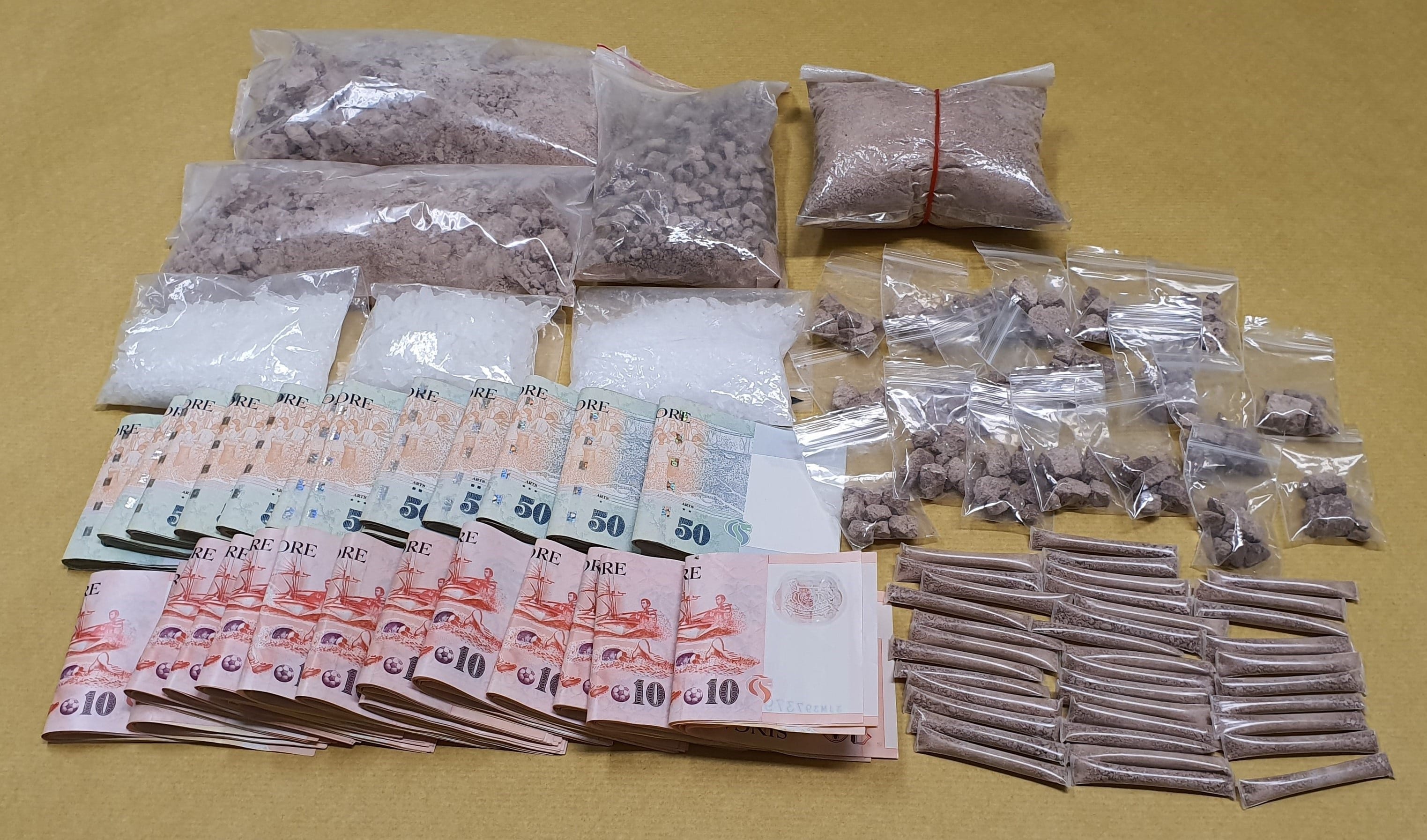 Singapore dollars and various drugs in plastic bags on a table.