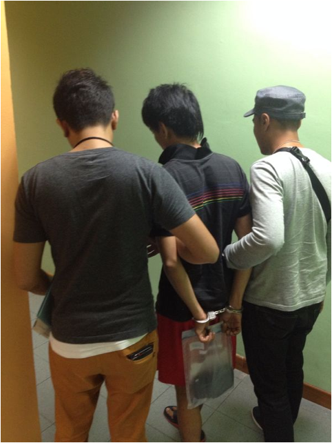 Two officers escorting a person in handcuffs, back view.