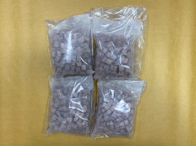 Four clear plastic bags filled with small, brown, cubed food pieces.