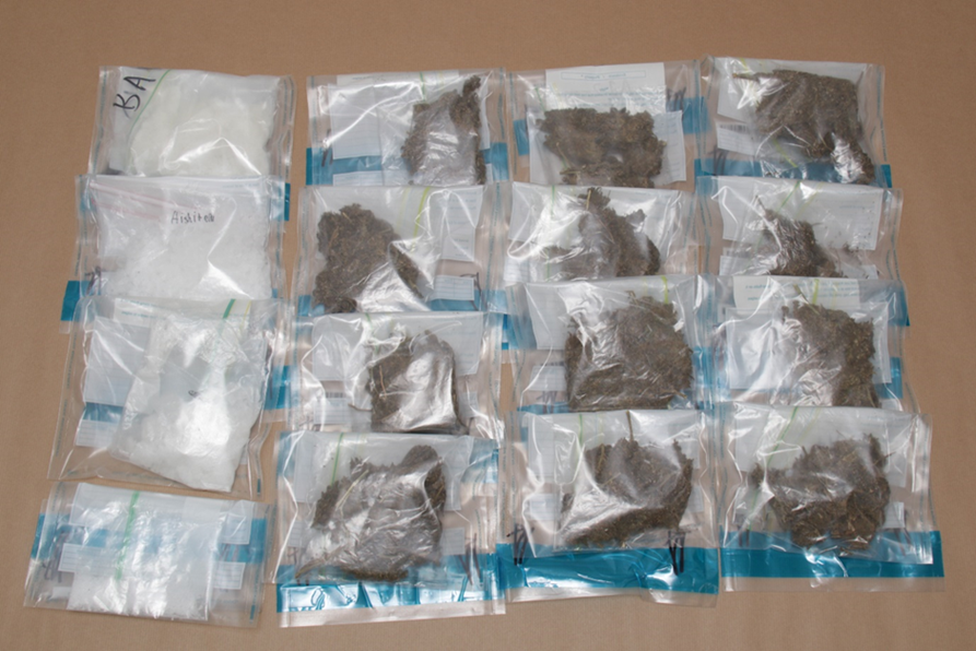 Fourteen plastic bags containing white and brown substances on a tan surface.